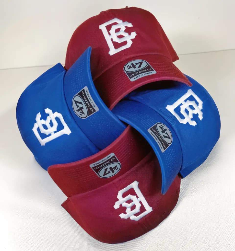 Stacks of red and blue caps embroidered with white monograms