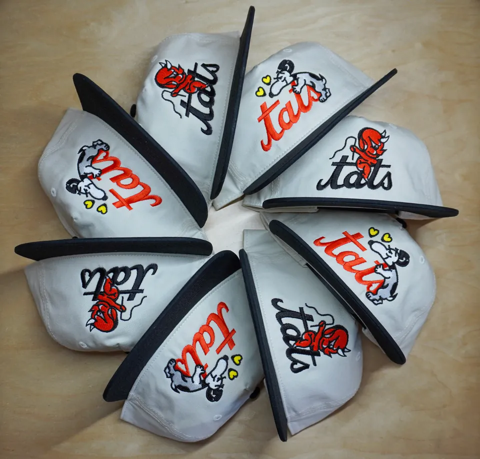 Gray caps arranged in a circle with colorful Tats embroidery