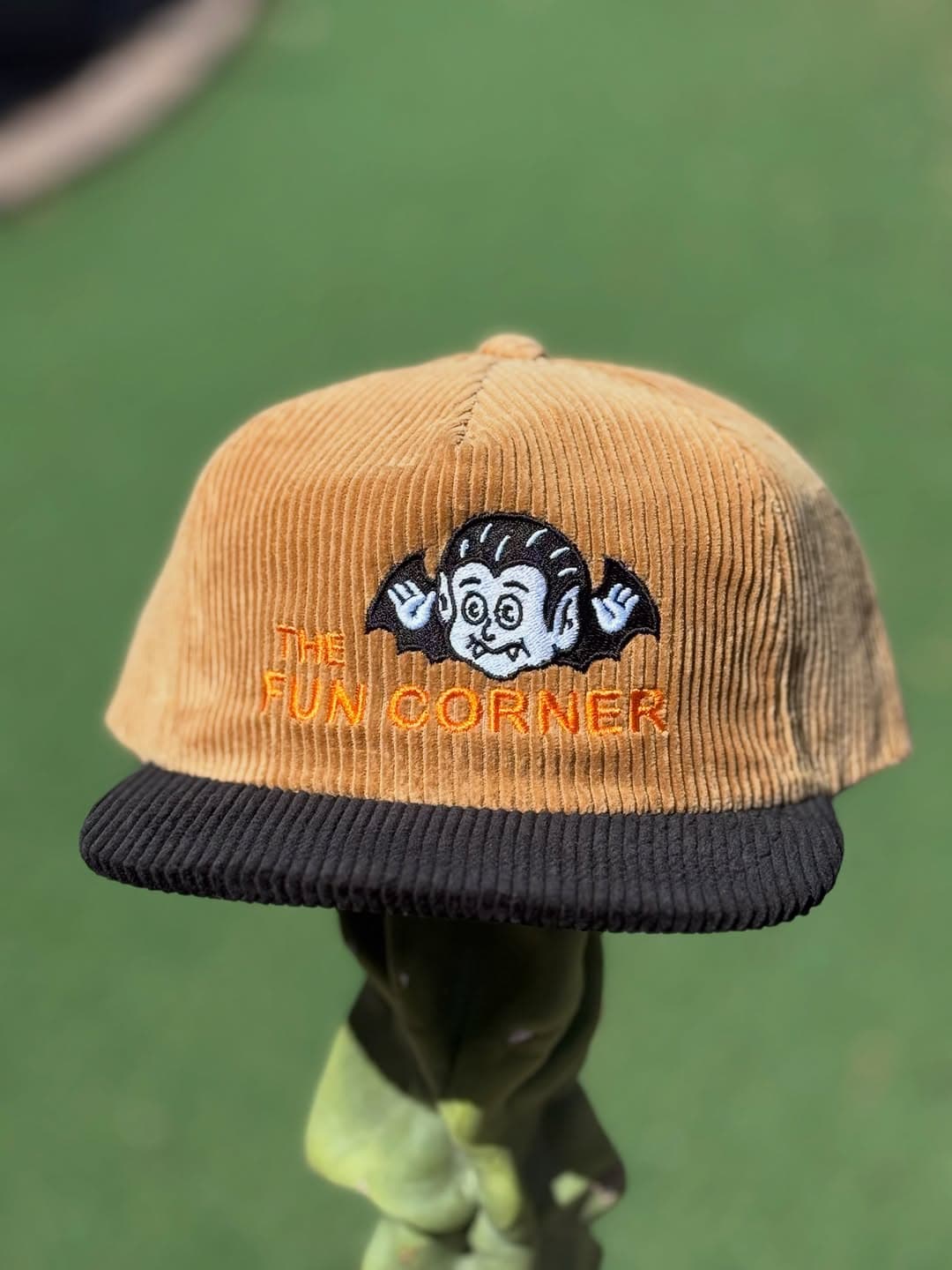A tan corduroy cap embroidered with The Fun Corner vampire artwork